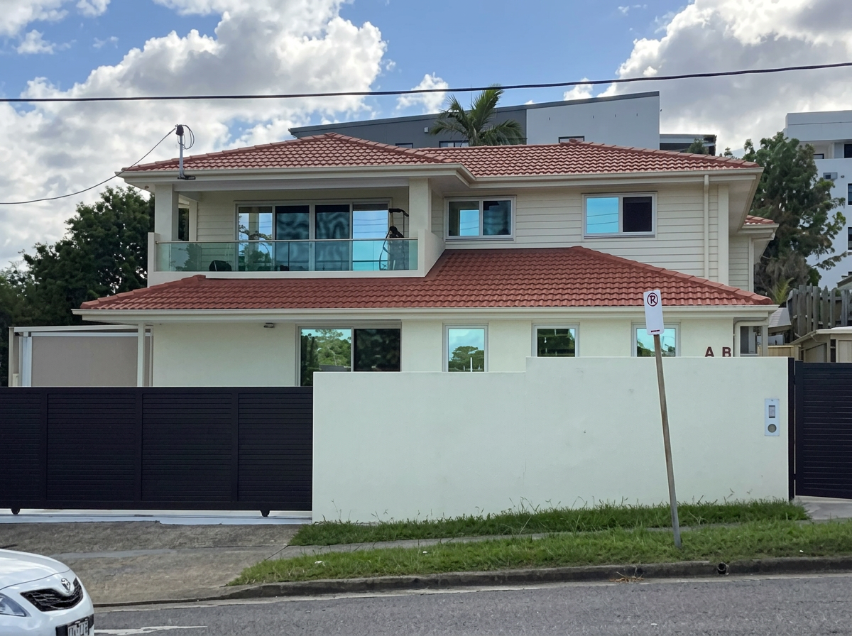 Large rendered home with terracotta roof and white perimeter wall